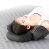 A person is using a black electric cervical neck massager while lying down on a gray surface.