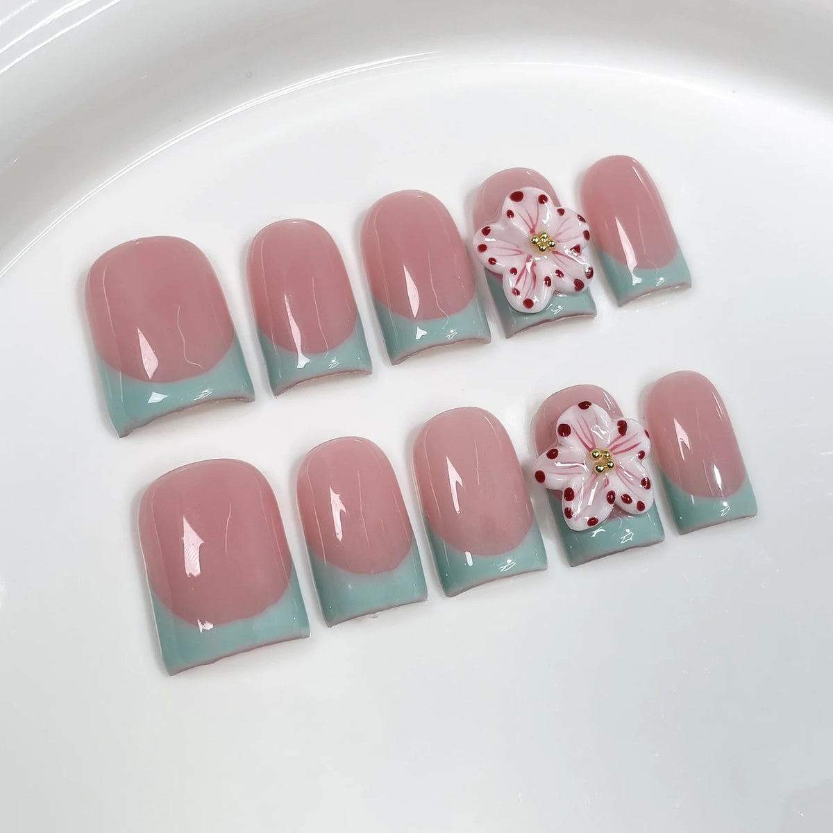 Un set de uñas postizas nude rosa con acabado brillante y delicados toques florales rosas.
