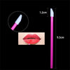A pink disposable lip brush with a nylon applicator wand shown next to a measurement scale.
