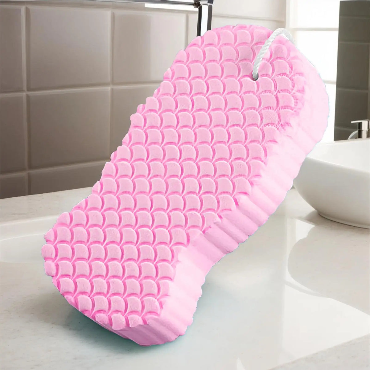 A pink exfoliating bath sponge set with a textured surface resting on a white countertop.