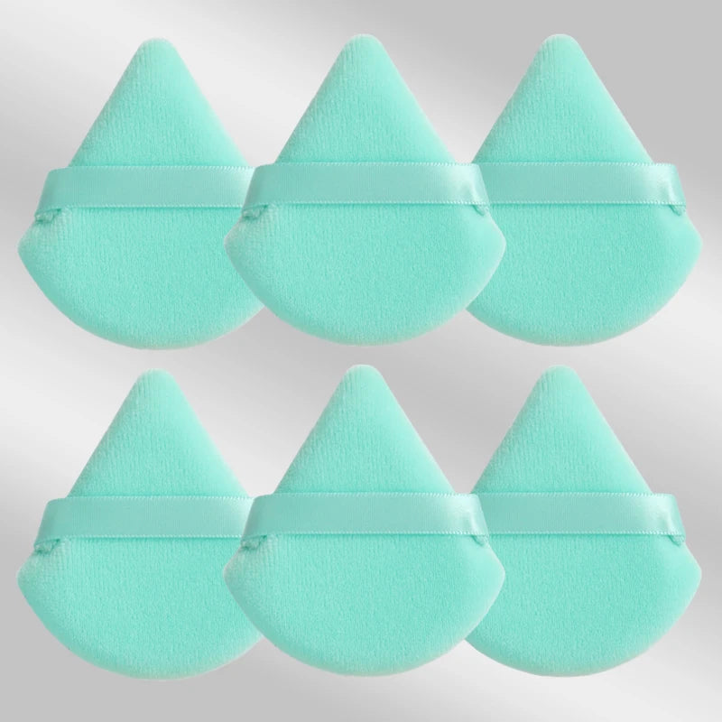 Un set de six éponges de maquillage triangulaires turquoise claires avec des élastiques.