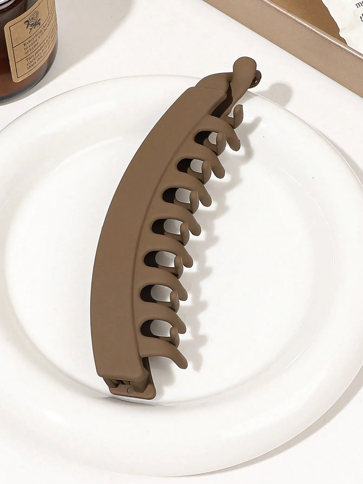 A brown banana hair clip is shown resting on a white plate.