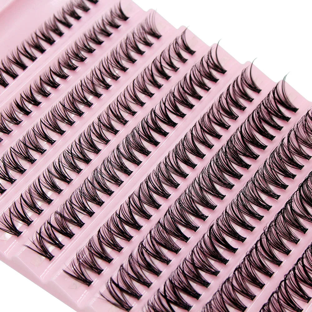 A pink plastic lash tray filled with black cluster lashes for eyelash extensions.