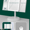 A white foldable LED makeup mirror with 2x and 3x magnification options displayed on a stand.