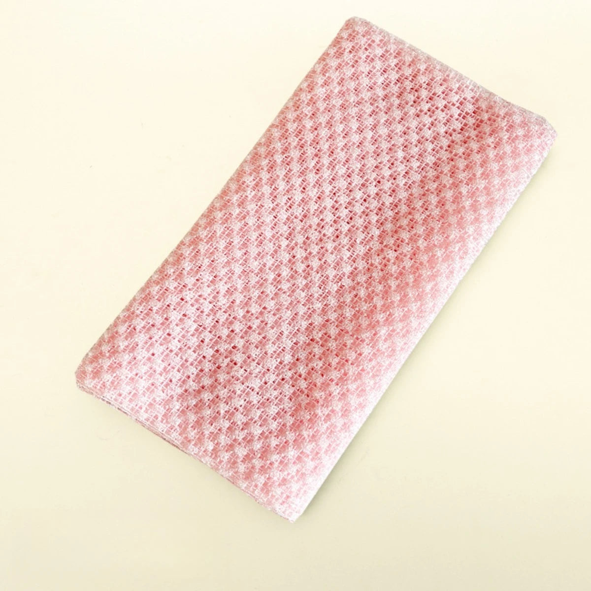 A pink exfoliating body scrubber loofah with a textured surface, shown diagonally on a light background.