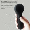 A hand holds a black silicone facial cleansing brush with a waterproof design against a background of water droplets.