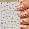 Close-up of a hand displaying watercolor mushroom nail art stickers on a fingernail.