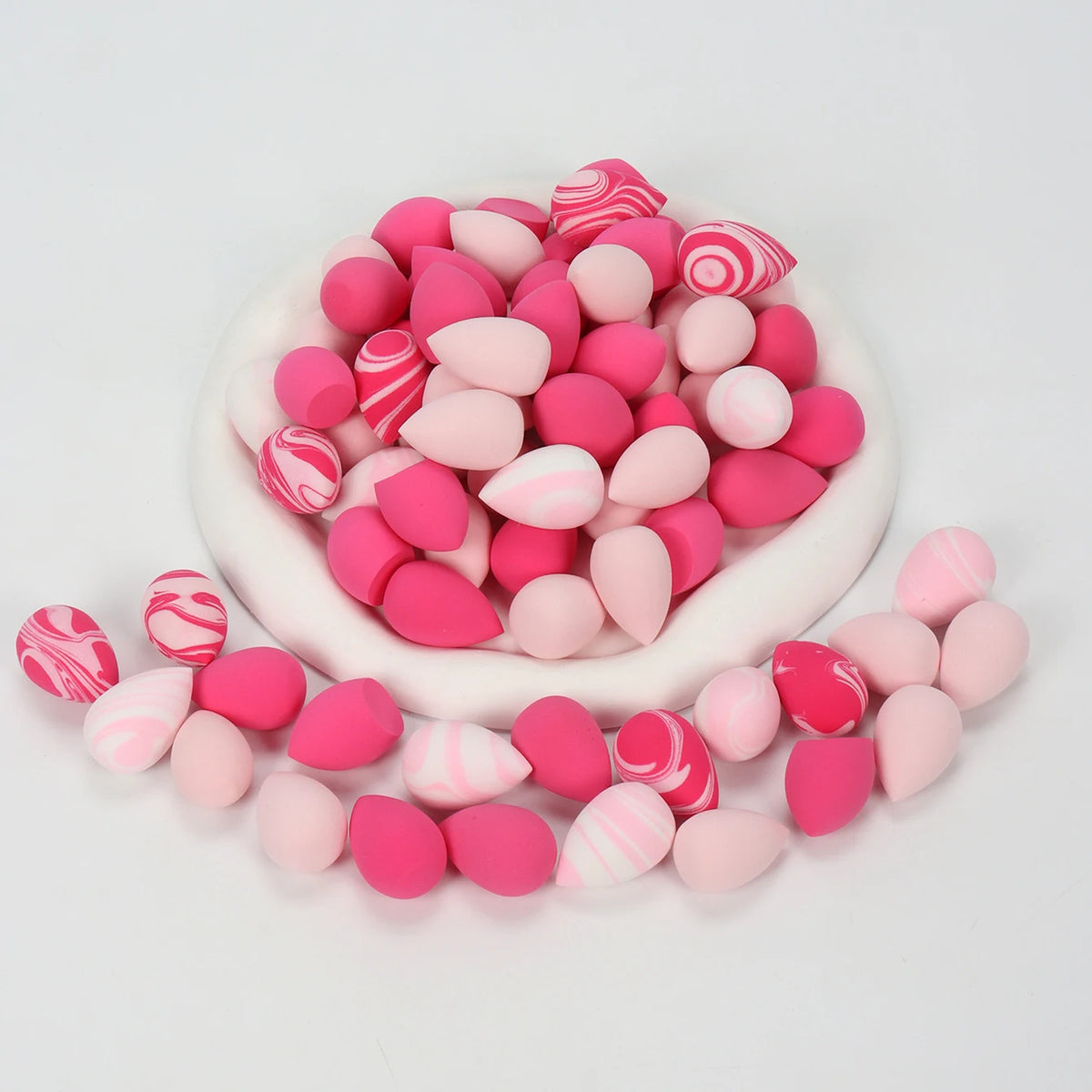 A pile of pink and white reusable expandable makeup sponges with various patterns.