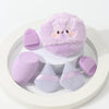 Un set de poudres légères lavande, comprenant un gros puff fluffy et plusieurs petits poudres roses et violets.