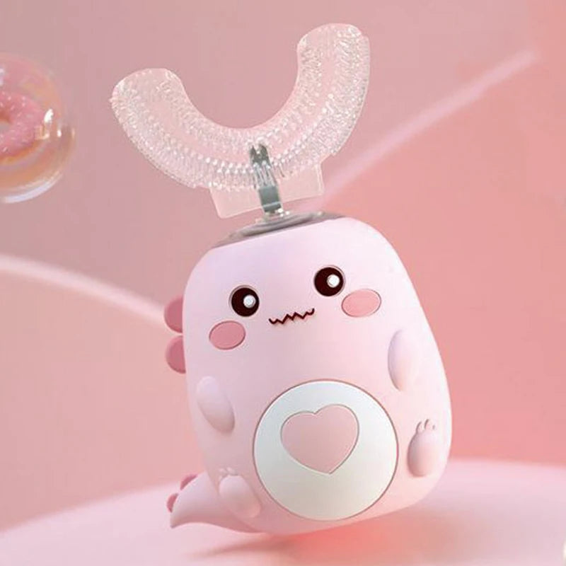 A pink, cartoon-shaped electric toothbrush with a U-shaped head and a heart design is shown against a soft pink background.
