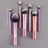 A set of seven professional makeup brushes in various sizes and shades displayed against a gray background.