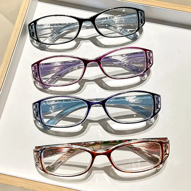 A set of four ultralight anti-blue light reading glasses with various colored lenses displayed on a white surface.