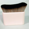 A makeup brush with black and tan bristles is shown in a pink rectangular container.