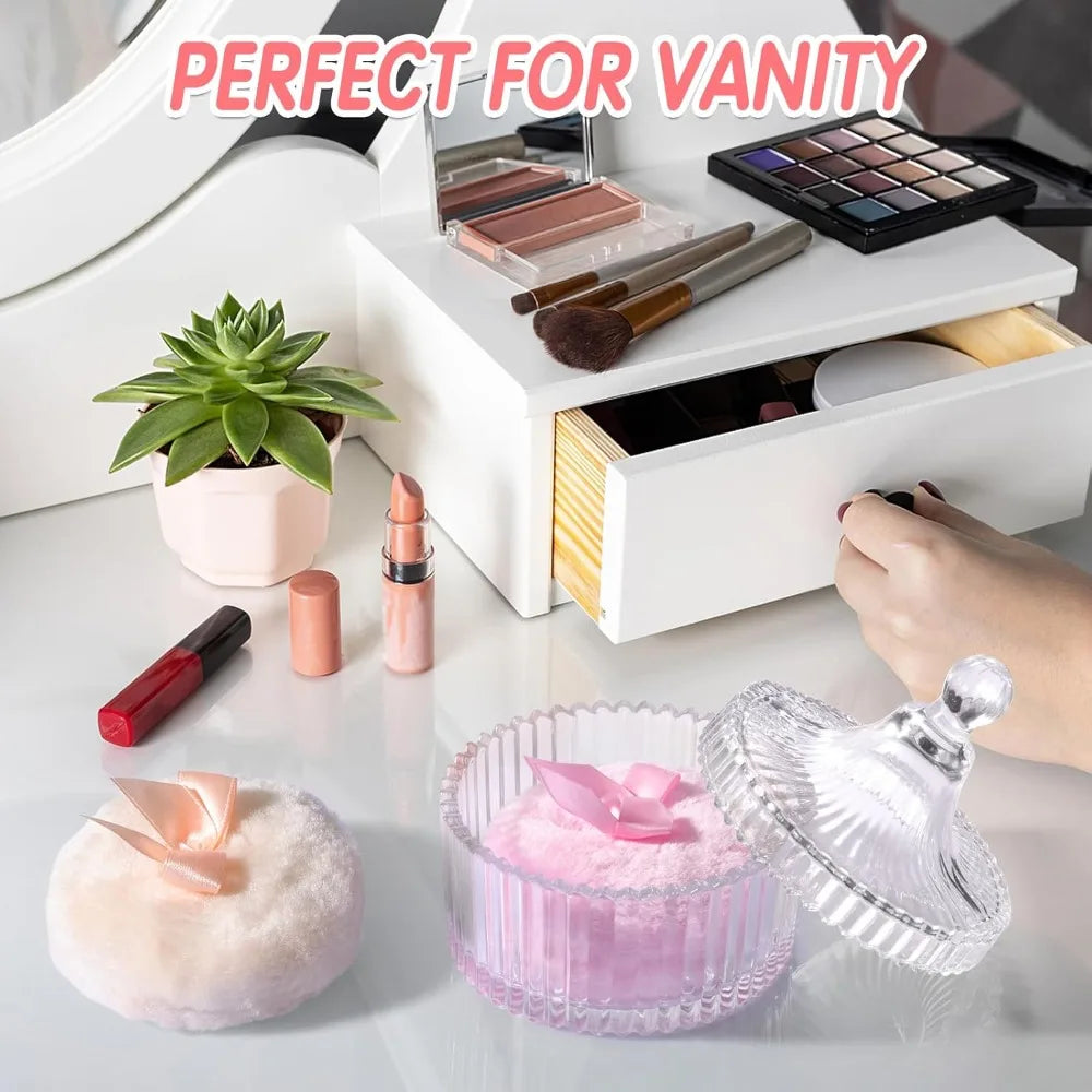 A white vanity display featuring a luxury velvet powder puff set with glass storage jar and various makeup items.