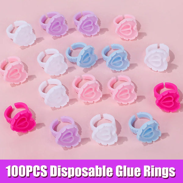 A collection of 100 disposable glue rings in various shades of pink and blue are displayed on a light pink background.