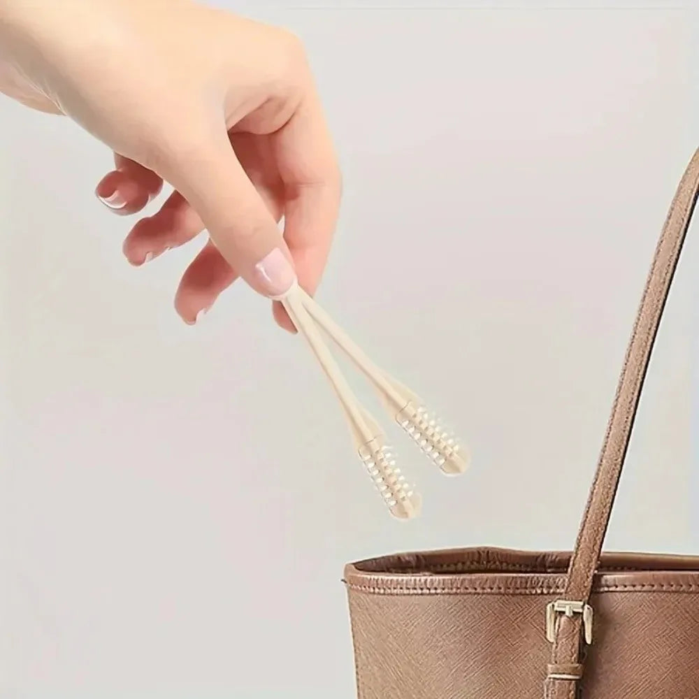 A hand is holding a set of nose and ear hair trimmers with wooden sticks and bristles above a brown storage container.