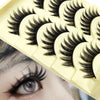 A close-up of a yellow plastic lash tray with five pairs of long, thick black false eyelashes.