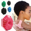 A woman is using a pink silicone exfoliating shower scrub brush and several black and blue silicone exfoliating brushes.