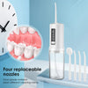 A clear portable oral irrigator device with a silicone tip and a glass container is shown next to dental models.