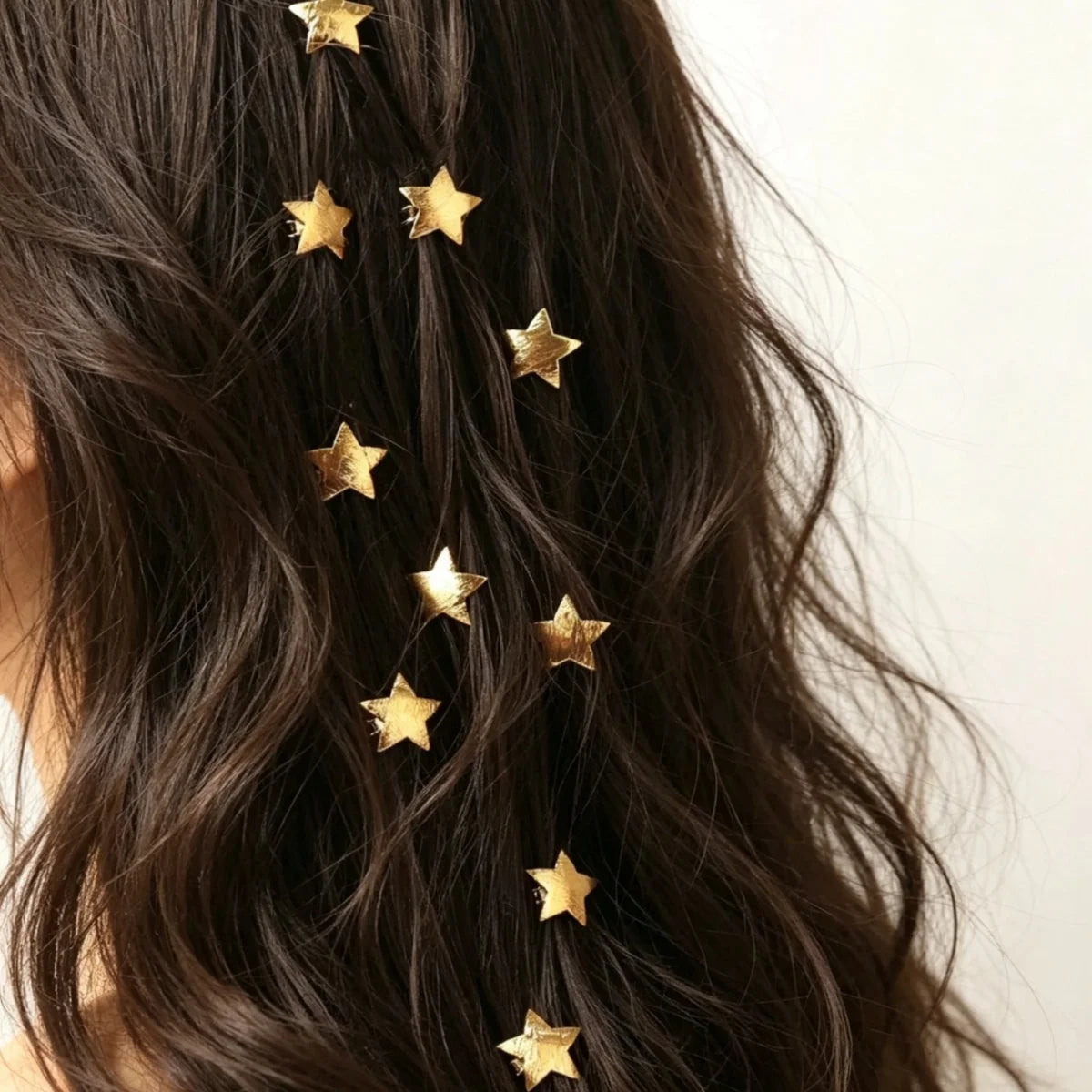 A close-up of dark hair adorned with ten gold star-shaped hairpins.
