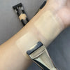 A close-up of an ultra-fine oval foundation brush being used on a wrist for makeup application.