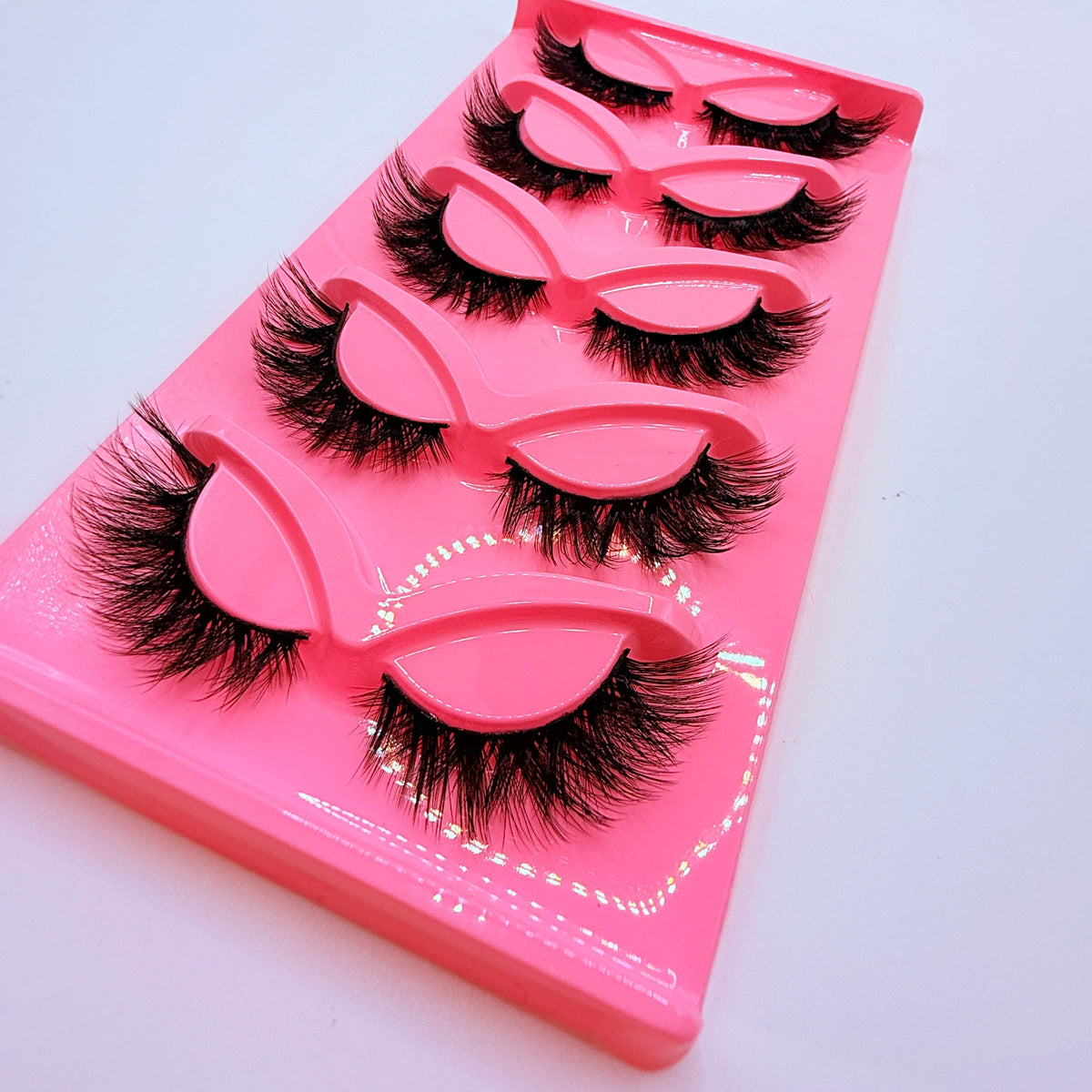 Un étui en plastique rose contenant cinq paires de faux cils dramatiques.