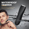 A close-up of a black waterproof trimmer being used on a man's face while water splashes around him.