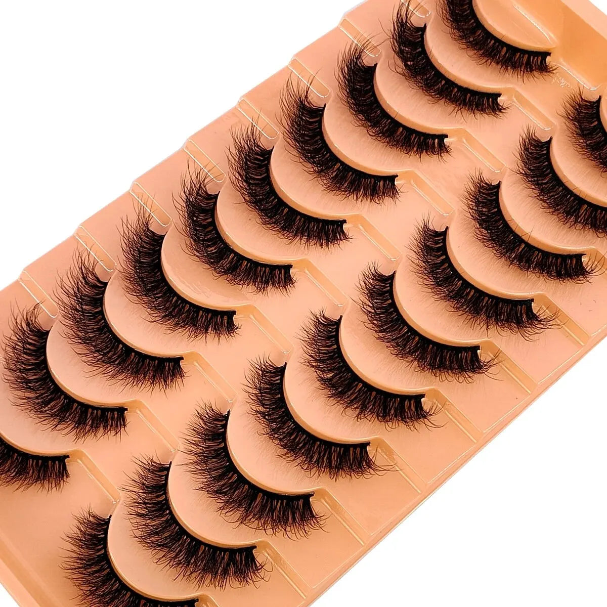 Un plateau de faux cils de renard faits à la main, de couleur pêche ou nude, disposés pour exposition.
