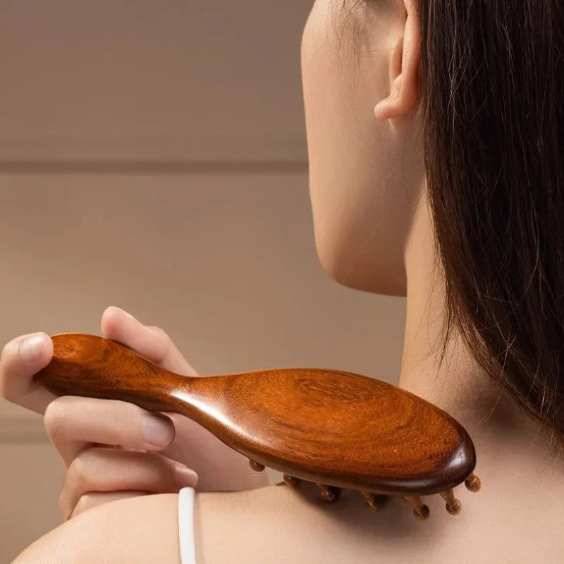 Una mano sostiene un peine de madera para peinar el cabello contra el pelo de una persona.