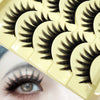 A close-up of a yellow false eyelash strip product showing several pairs of long black lashes.