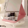 A pink foldable portable makeup mirror with measurements marked, resting on a white surface.