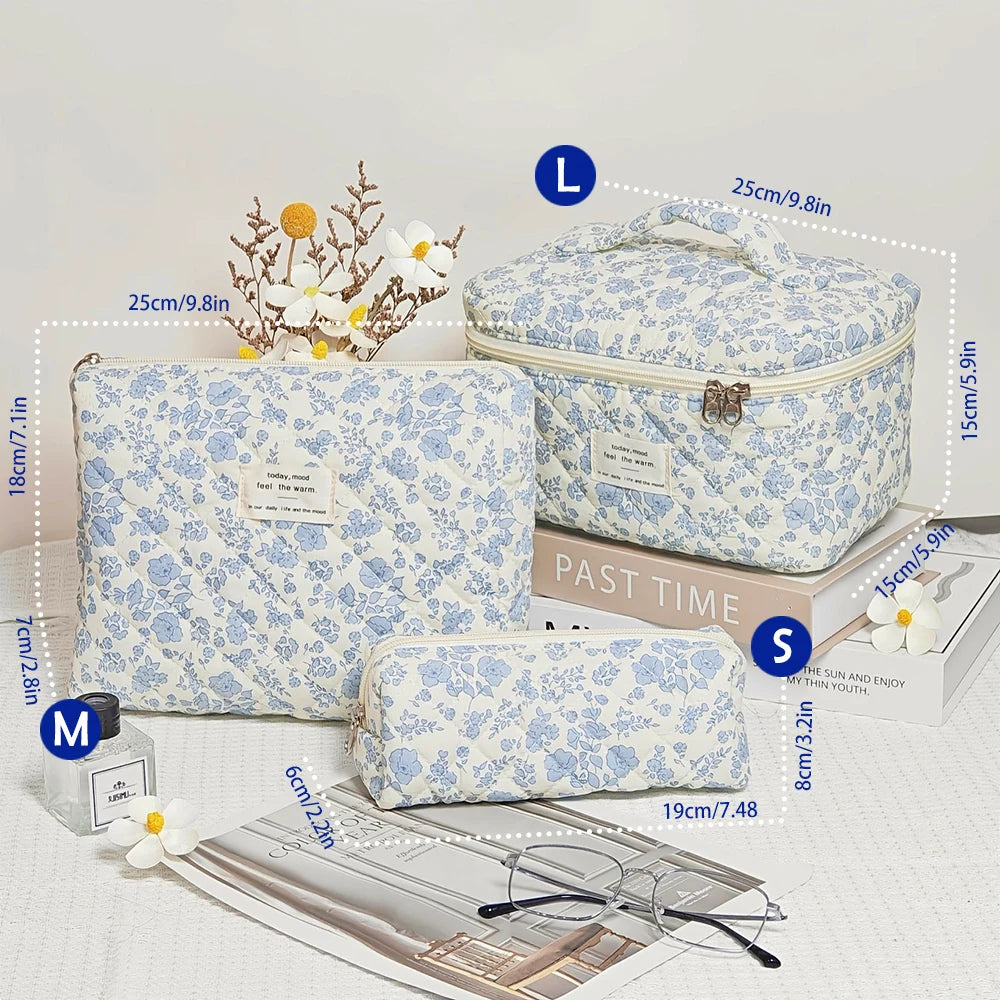 A light blue floral quilted cotton makeup bag shown with various sizes and a pair of glasses.