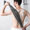 A man is using an exfoliating back scrubber bath towel on his back.
