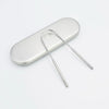 A stainless steel tongue scraper with a handle resting on a white surface.