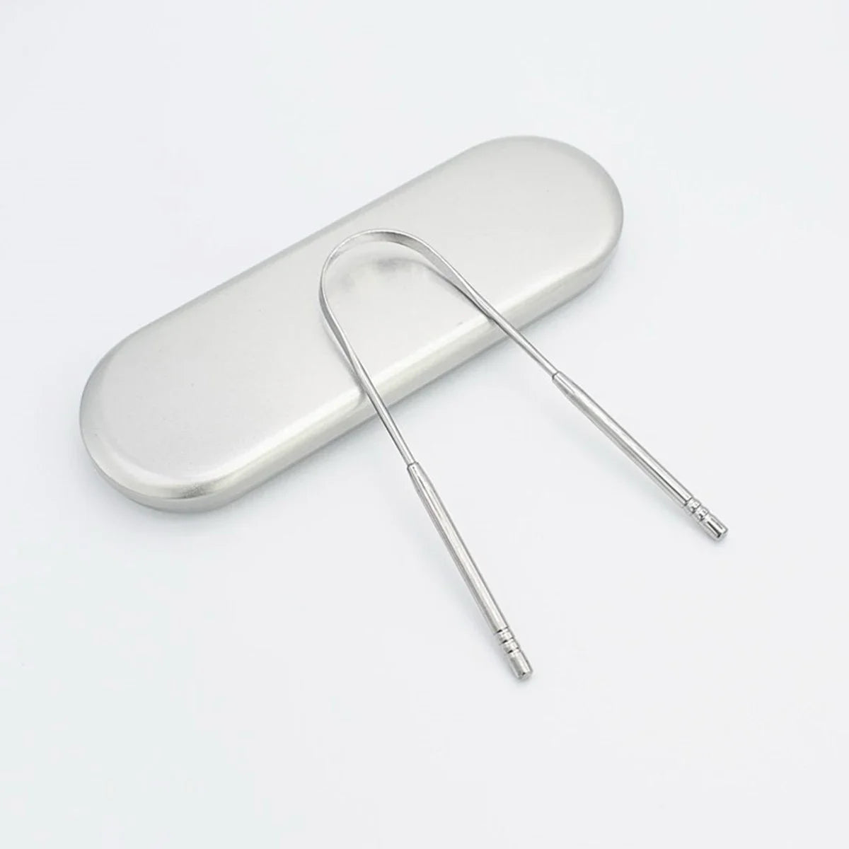A stainless steel tongue scraper with a handle resting on a white surface.