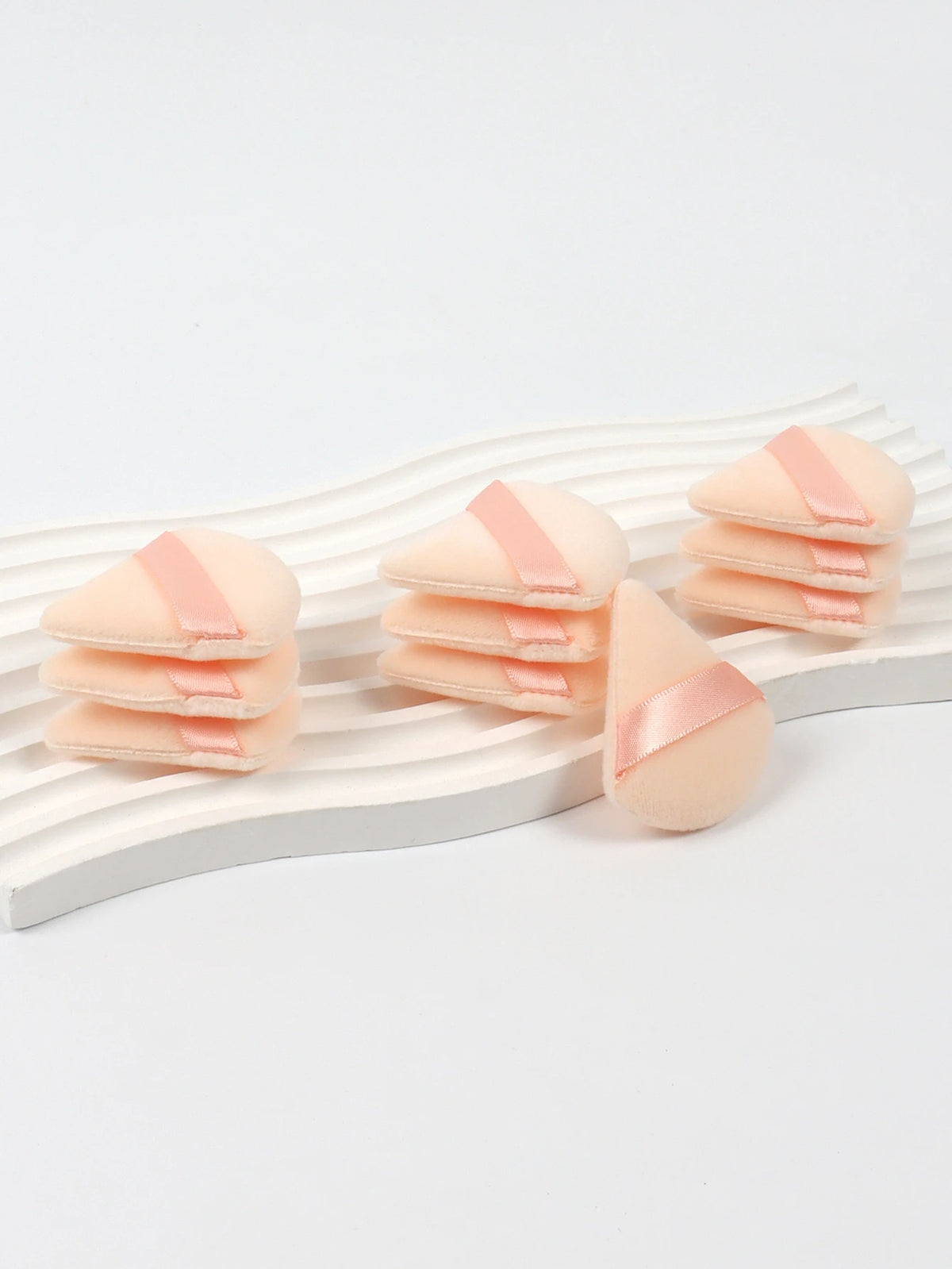 Un ensemble de puffs triangulaires roses disposés sur une surface en bois blanc.