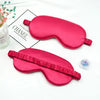 Two pink silk sleep eye masks are displayed on a white background next to a box labeled Chanel.