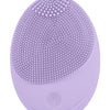 A purple electric sonic facial cleansing brush with a textured silicone head and a smooth base.