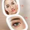 A compact LED makeup mirror showing a woman's face with 5x magnification.