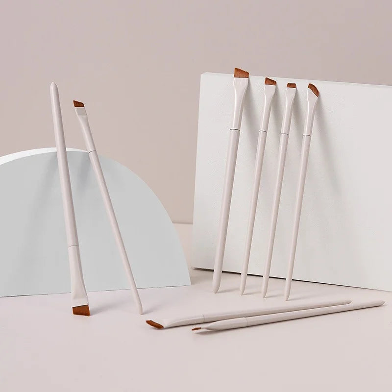 A set of precision angled eyeliner and eyebrow makeup brushes with light wood handles displayed on a white background.