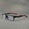 Gafas deportivas para leer anti-luz azul negras con detalles rojos, apoyadas sobre una superficie gris.