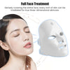 A woman is applying a white facial mask to her face, demonstrating full face treatment for skincare.