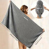 Serviette de cheveux en microfibre grise, présentée à plat et enveloppée autour de la tête d'une personne.