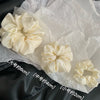 Une collection de pinces à cheveux en satin chiffon de couleur crème et de différentes tailles sont présentées sur du papier 