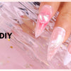 Close-up of a hand displaying 3D gel nail DIY art on fingers against a pink background.