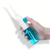Une main tient un irrigateur dentaire manuel portable avec un corps blanc et bleu et une pointe transparente.