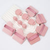 A set of twelve pink makeup sponges and applicators with pink accents arranged on a white surface.