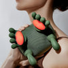 A hand is holding a green silicone massager with orange tips, demonstrating its use for neck and shoulder relief.