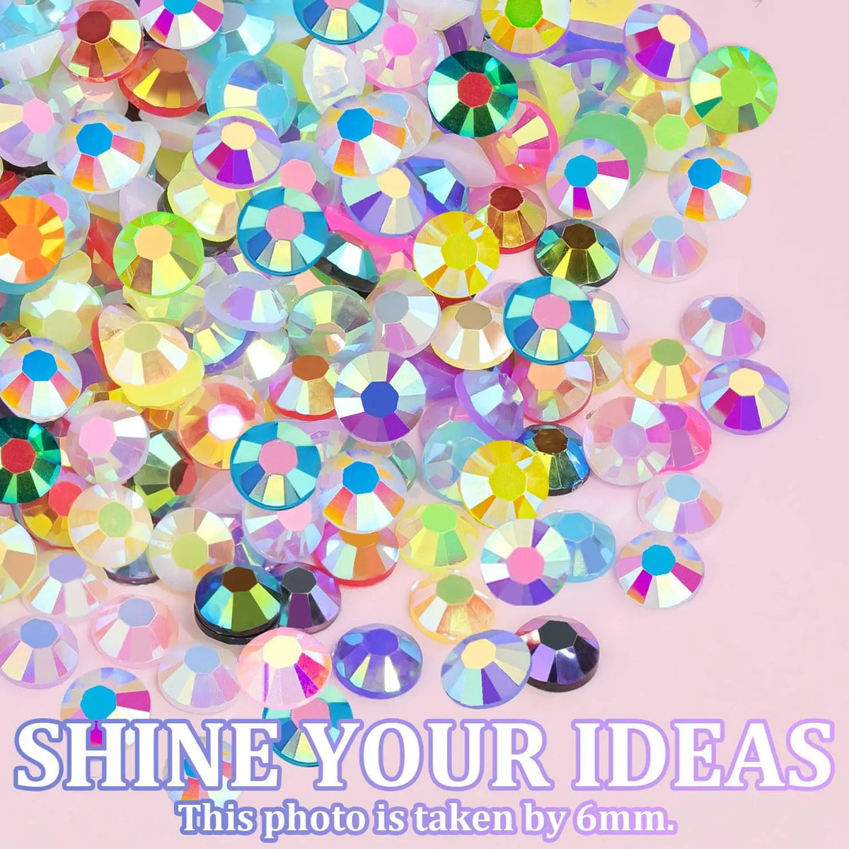 A pile of colorful, iridescent rhinestone nail charms scattered on a light pink background.