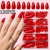 A hand displays a set of glossy red press-on nails with various shapes and shades arranged in a clear plastic container.